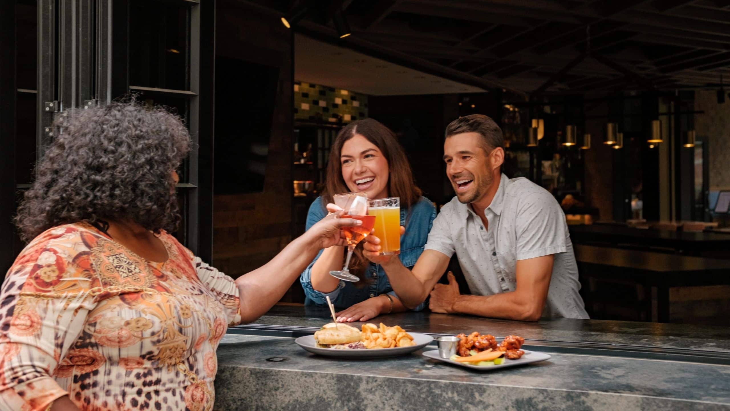 Friends toasting drinks and sharing food together at a lively bar